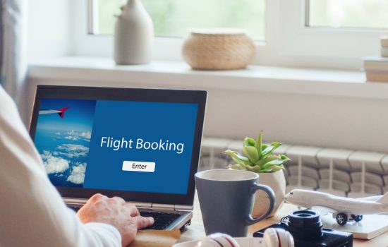 Close up of young man booking flights working on the notebook Close up of young man booking flights working on the notebook indoor. Selective focus on the notebook.